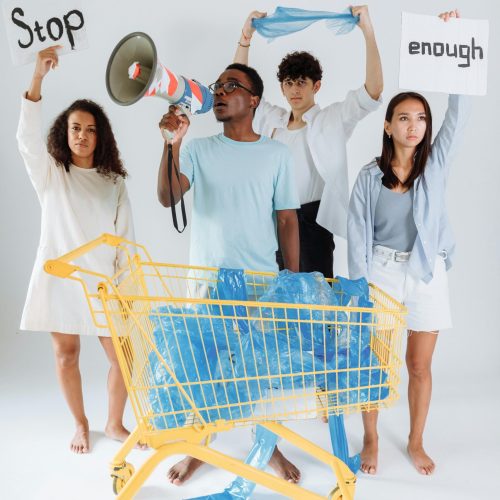 Group of young adults protesting against plastic waste with signs and a megaphone.